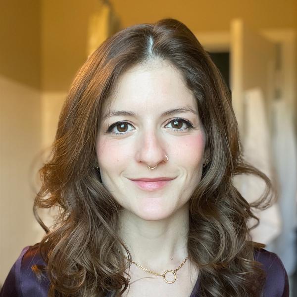 Image of a white woman with wavy shoulder-length brown hair wearing a dark purple shirt.